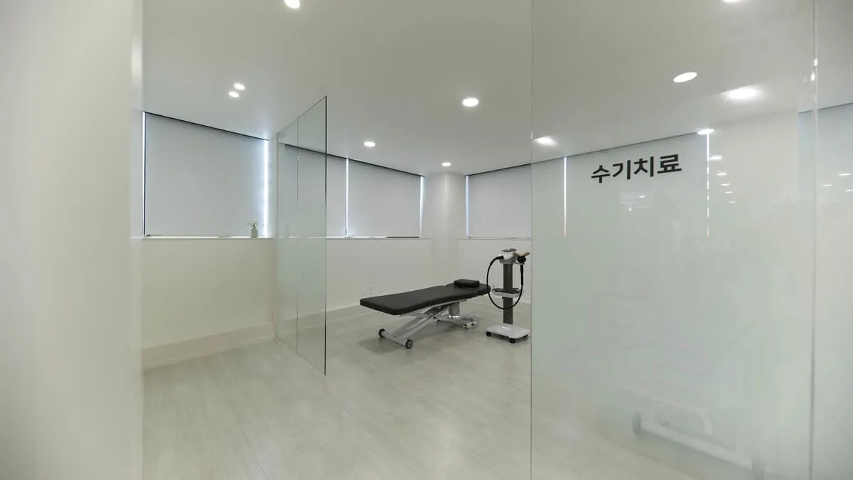 유리문에 수기치료라고 적힌 개인 치료실 안의 치료 베드와 도르래식 운동 기구